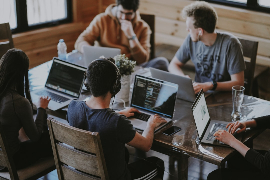 Team collaborating over laptops in a workspace